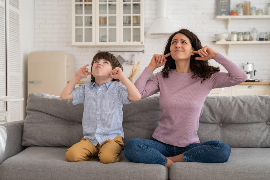 mom and son plugging ears and looking angry about noisy tenants upstairs